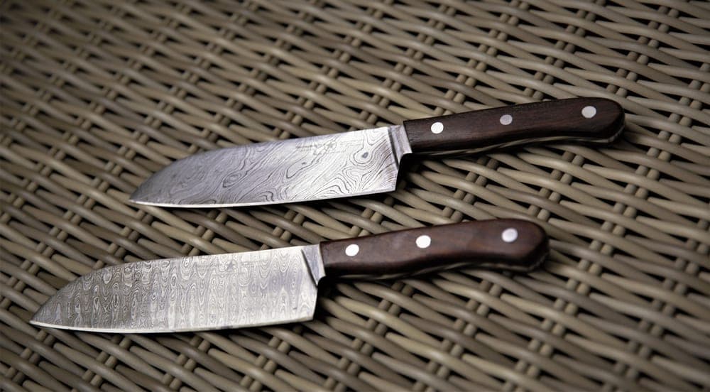 Two kitchen knives placed side by side on a dark surface