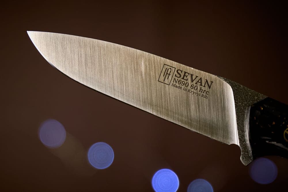 A knife blade with a dark finish photographed close up