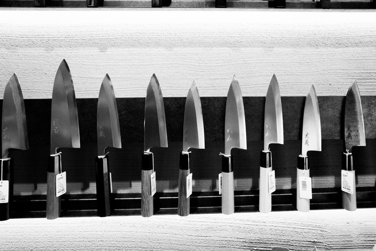A row of Japanese kitchen knives displayed against a dark background