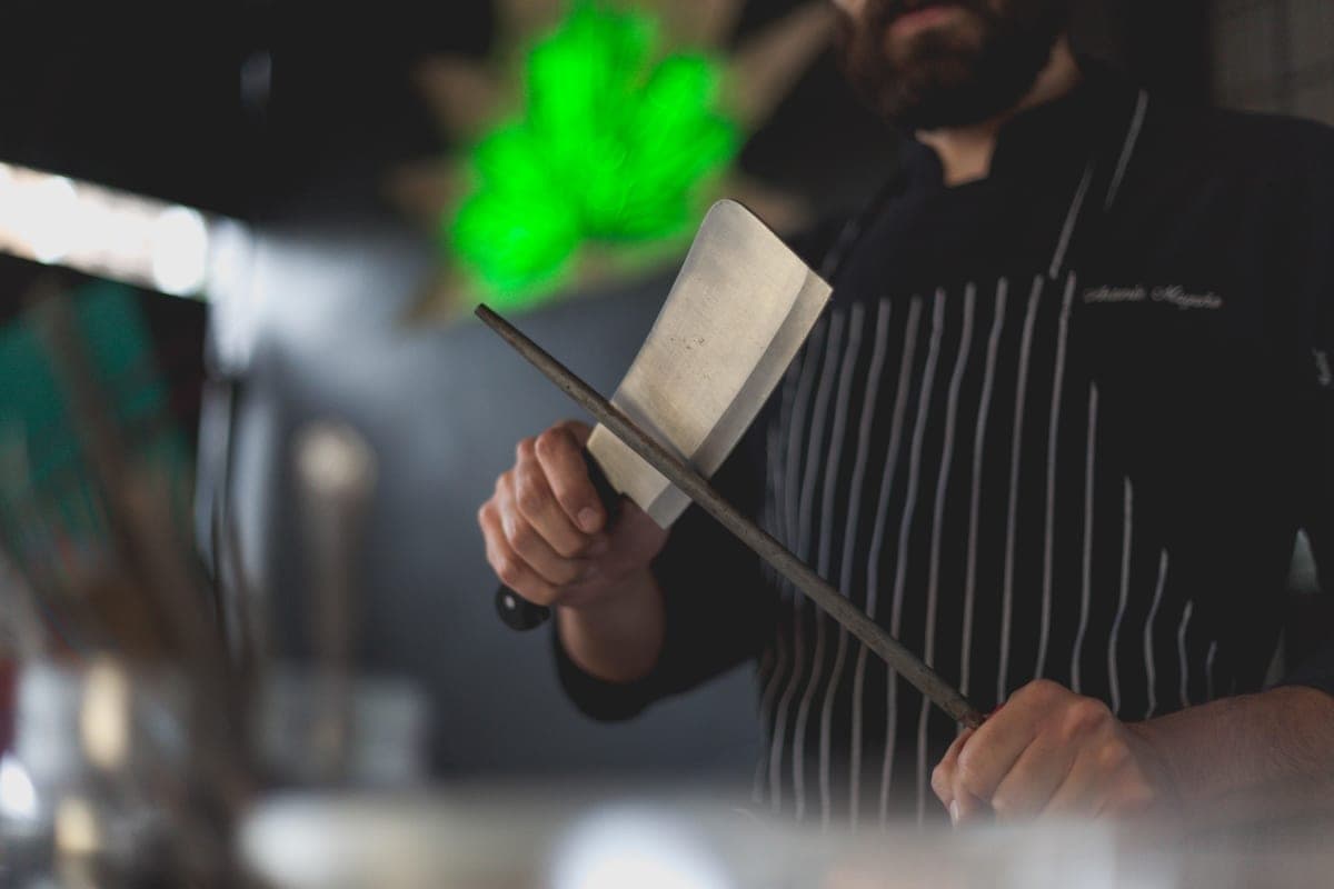 A cook wiping down a kitchen knife with a cloth