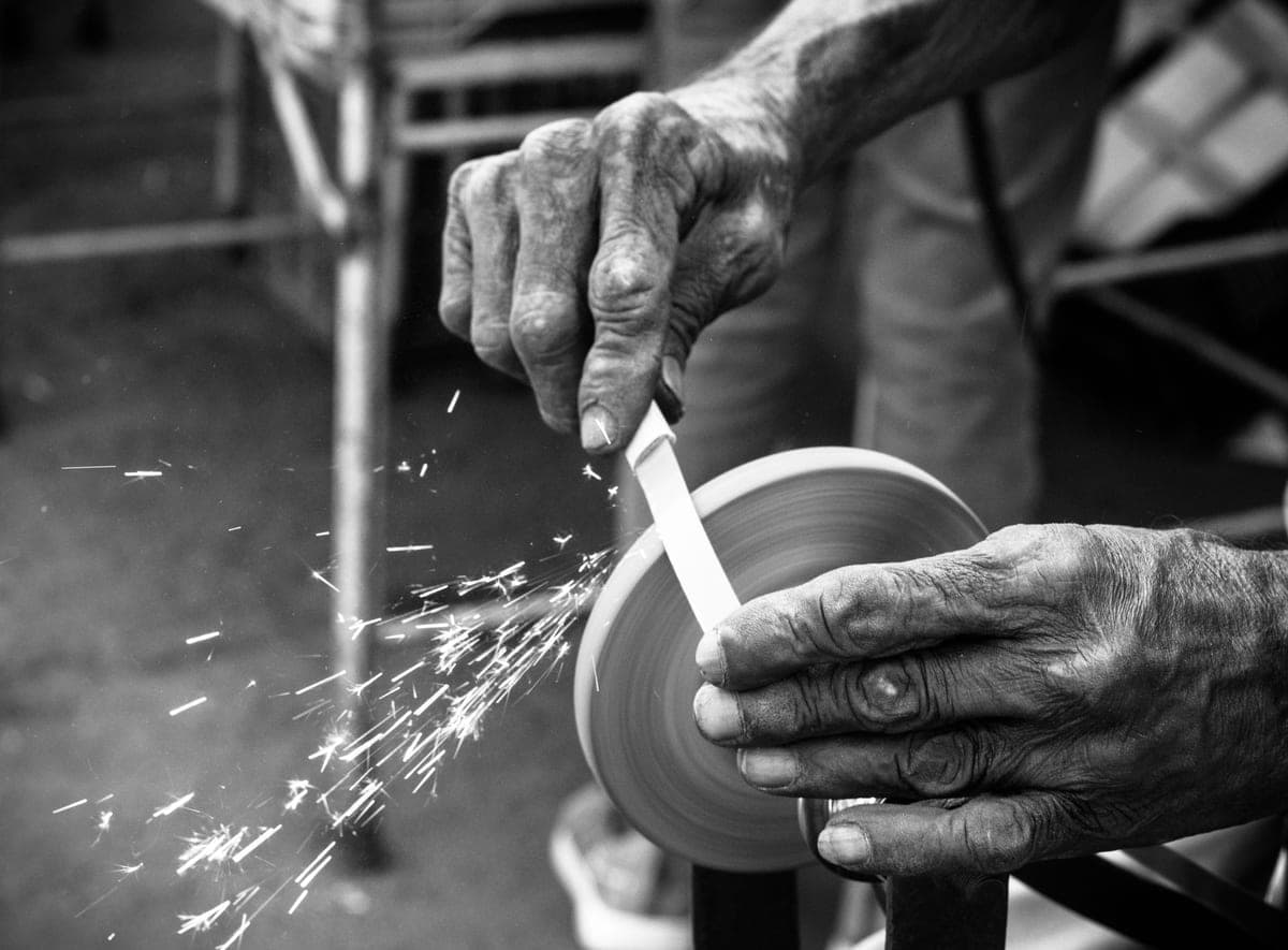 A craftsman working a blade in a sharpening workshop
