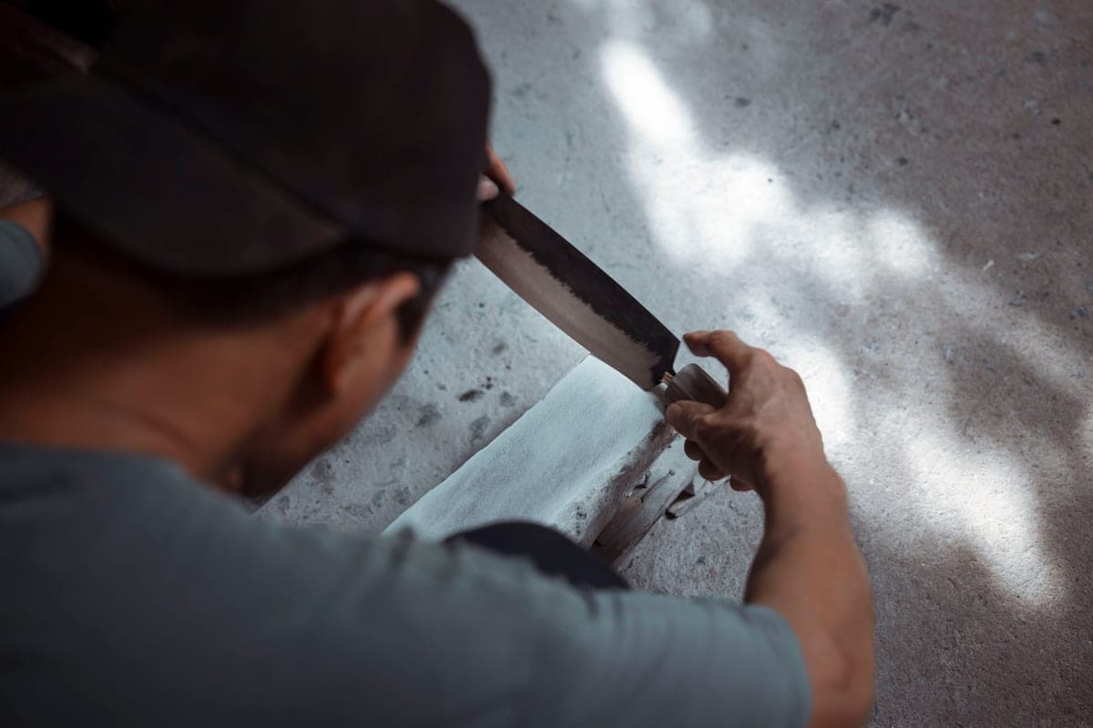 A person drawing a knife blade across a wet sharpening stone