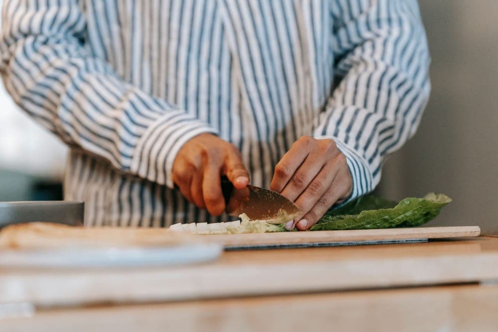A home cook working at a kitchen counter with a knife and board